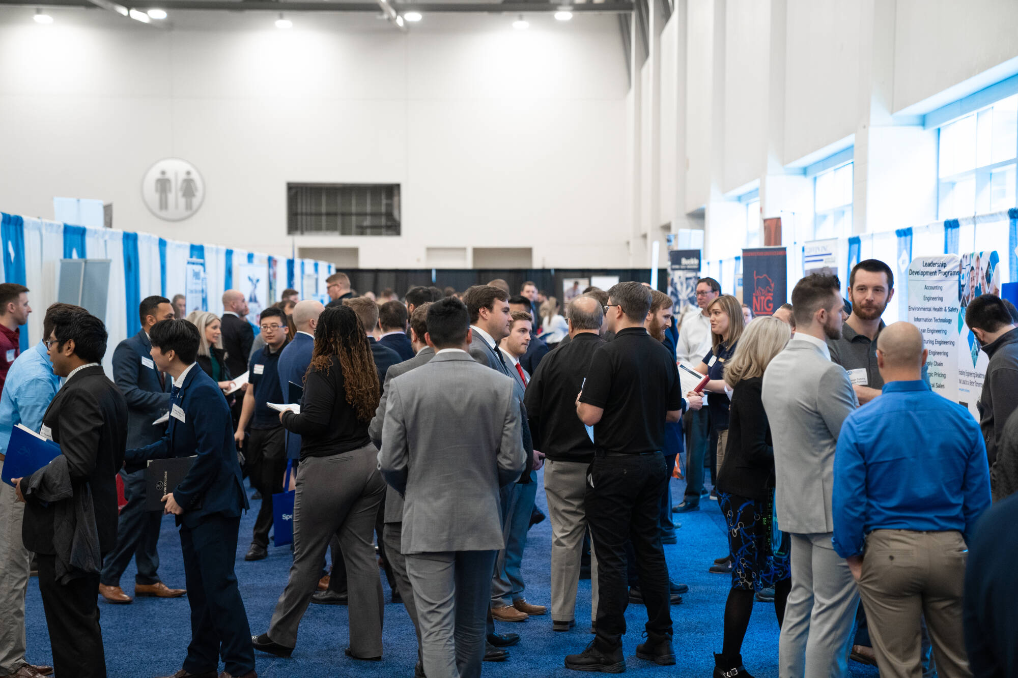 A group of people dressed in business attire, attending a career fair.